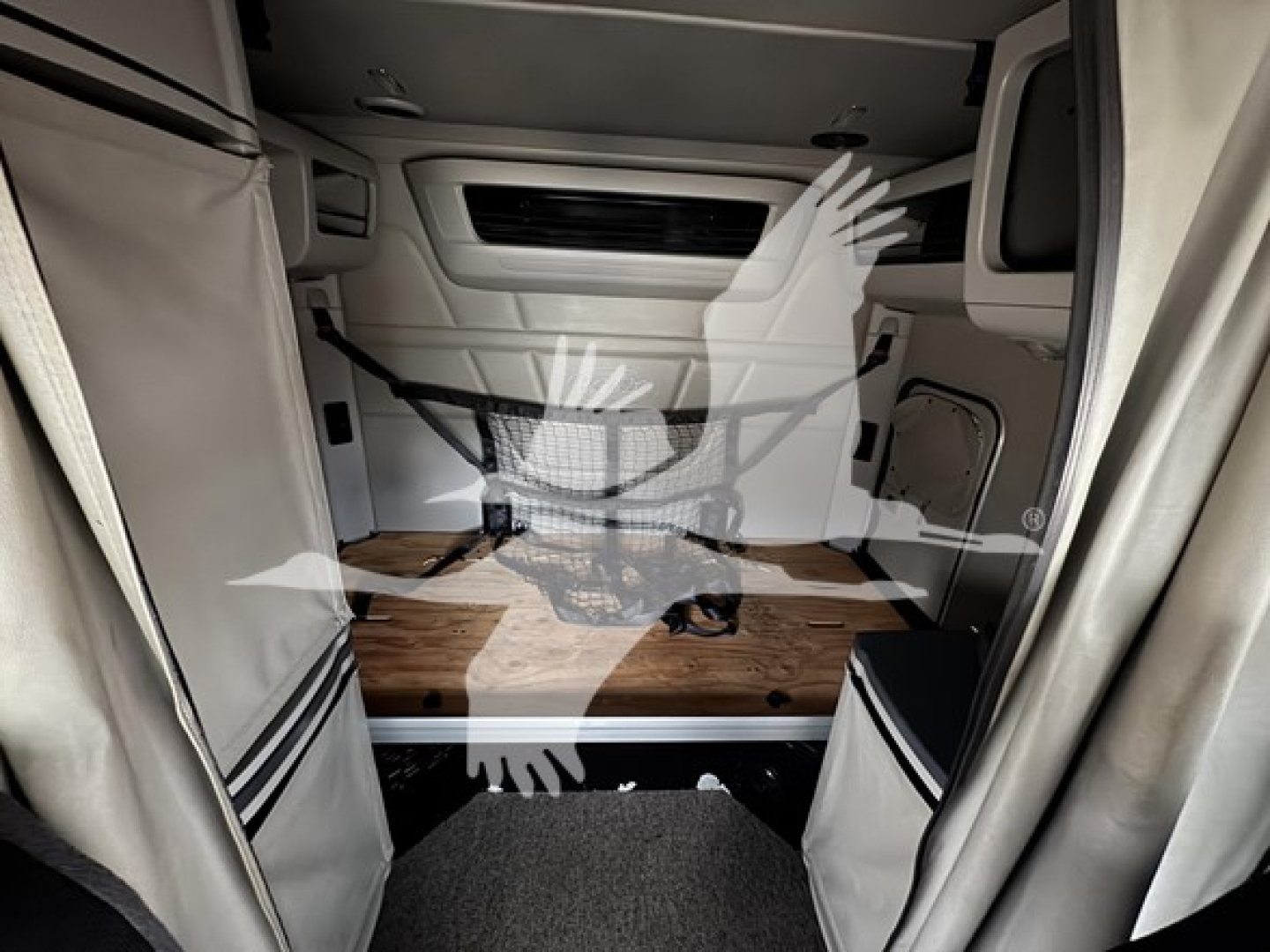 Peterbilt 579 sleeper cab interior cargo area showing raised driver's cabin, wood flooring, and storage walls.