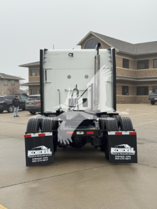 Peterbilt 579 tractor rear view showing dump trailer connection and mud flaps with Kordell logos.