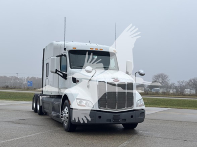 Peterbilt 579 conventional sleeper truck in a parking lot, front three-quarter view.