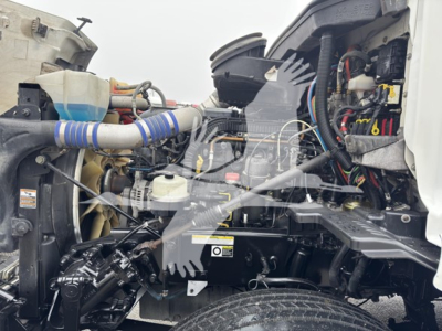 Peterbilt 579 engine bay with visible hoses and components in view from the passenger side; various wiring harnesses, air intake, and coolant reservoir visible.