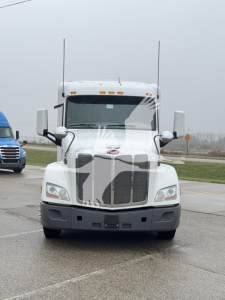 Peterbilt 579 conventional sleeper truck front view with chrome grille and dual antennas.