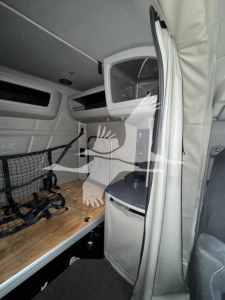 Peterbilt 579 interior sleeper cab showing bunk area with wooden platform, storage nets, overhead cabinet and seating along the side.