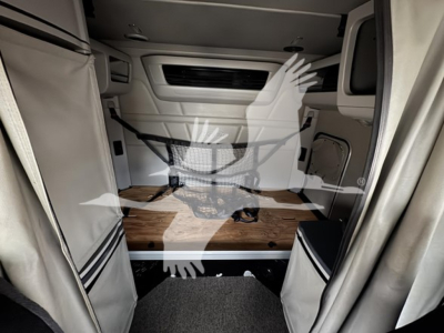 Peterbilt 579 sleeper cab interior cargo area showing raised driver's cabin, wood flooring, and storage walls.