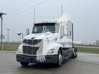 Truck cab in view showing Peterbilt 579 sleeper tractor with front grille, headlights, and white paint.