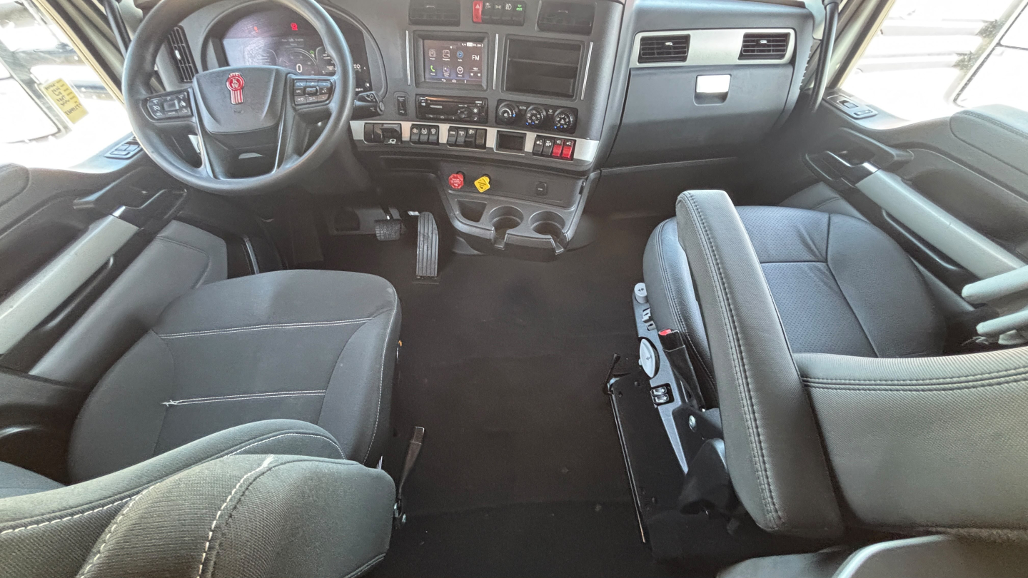 Kenworth T680 cab interior showing steering wheel, dashboard, and driver seat area.