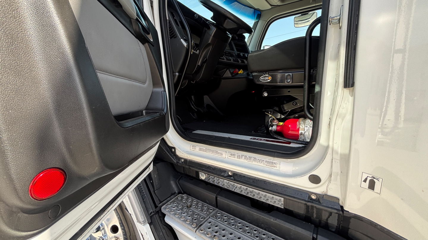 Kenworth T680 cab interior and entry door sill showing dashboard and driver's area.