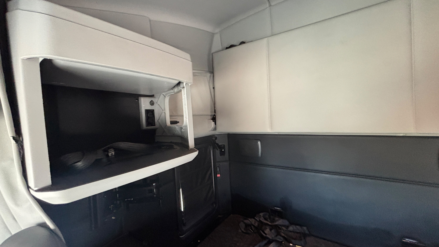 Kenworth T680 cab interior showing sleeper compartments and storage shelves with a small open compartment