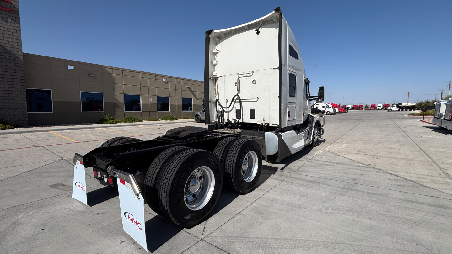 Kenworth T680 tractor-trailer cab from rear 3/4 view showing sleeper, dual rear axle, chrome fuel tanks, and rear mud flaps with Kenworth logo.