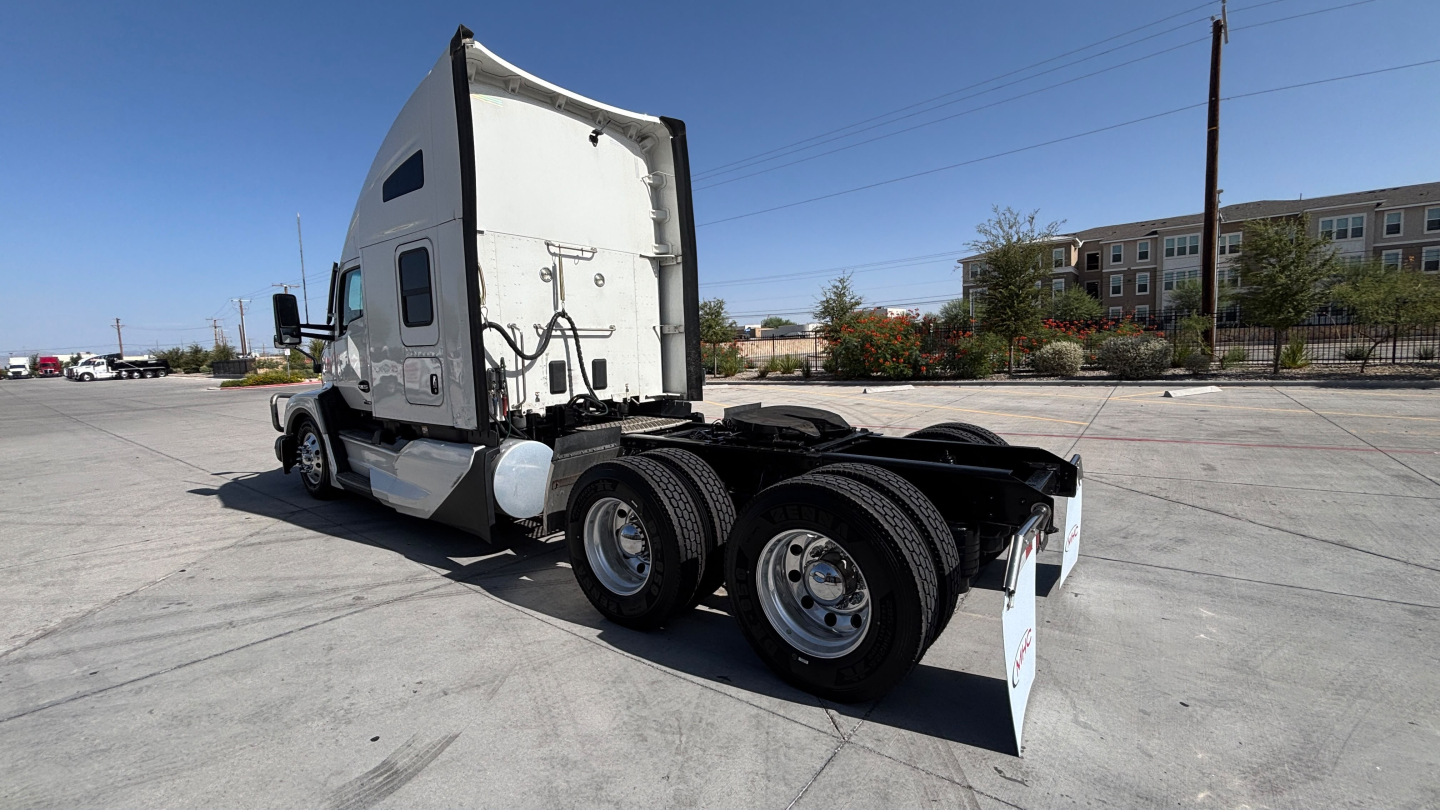Kenworth T680 tractor rear/side view showing dual rear axles and fifth-wheel, truck cab with sleeper, clear sky.