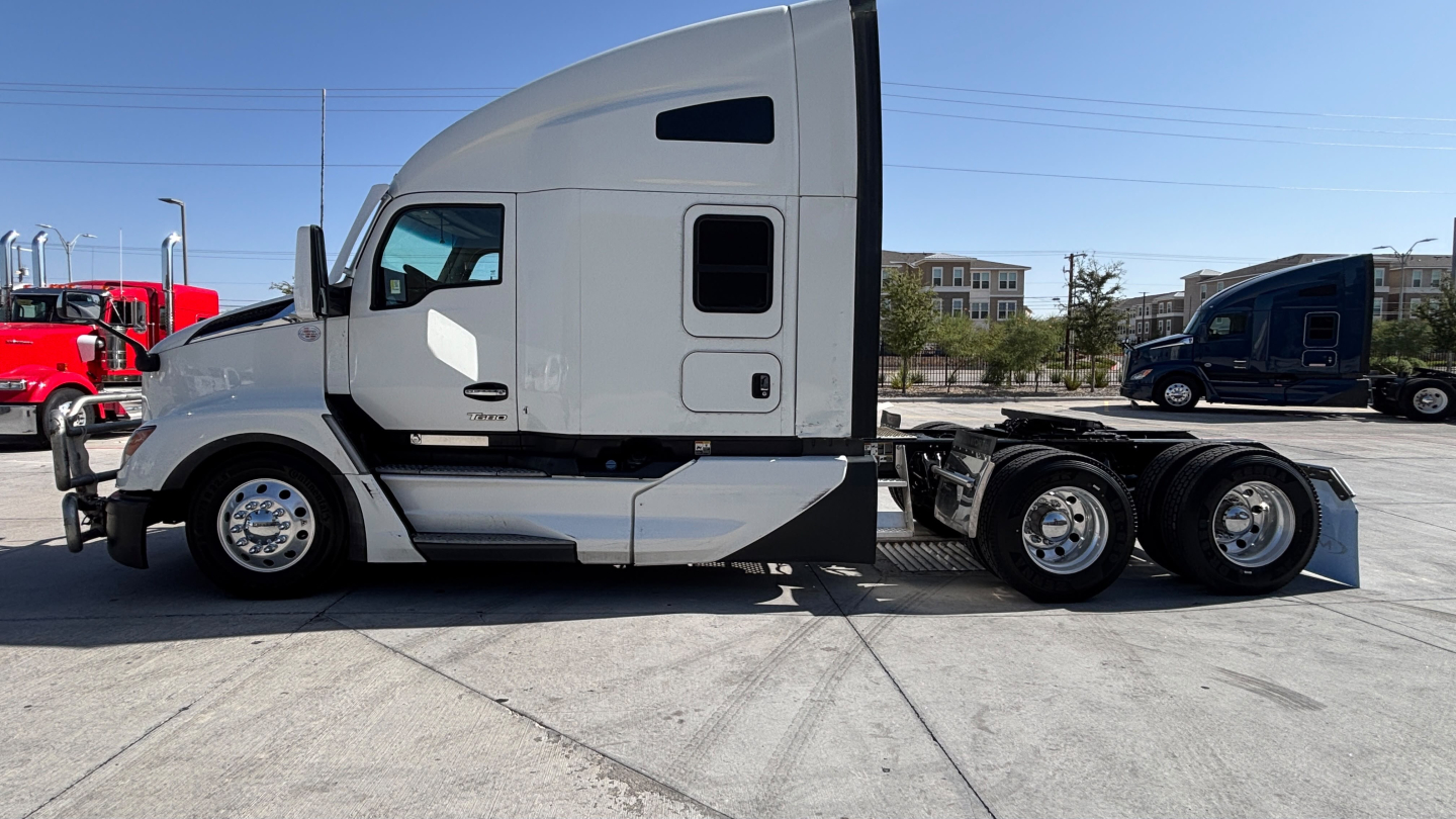 Truck side view showing Kenworth T680 sleeper cab and rear dual-axle tractor configuration with chrome wheels.