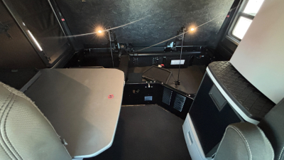 Kenworth T680 cab interior showing sleeper area with light gray upholstery, storage cabinet, and control panels.