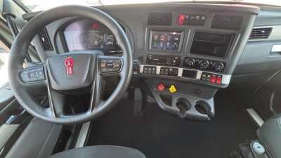 Kenworth T680 dash and steering wheel showing instrument cluster and center console with controls and touchscreen display.