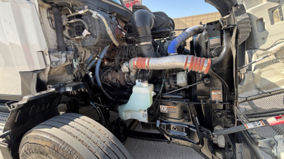 Kenworth T680 engine bay showing coolant reservoir and various hoses and components.