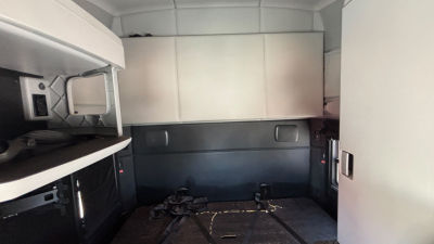 Kenworth T680 sleeper cab interior cargo area with storage cabinets and overhead compartments.