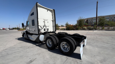 Kenworth T680 tractor rear/side view showing dual rear axles and fifth-wheel, truck cab with sleeper, clear sky.