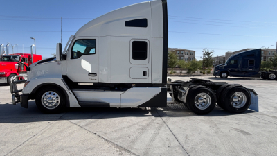 Truck side view showing Kenworth T680 sleeper cab and rear dual-axle tractor configuration with chrome wheels.