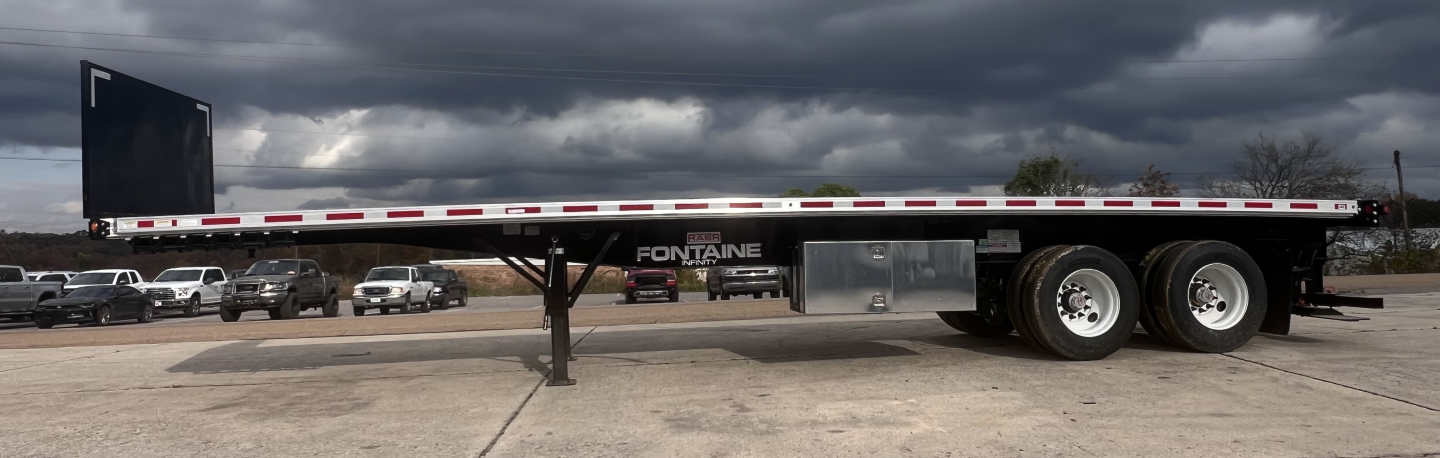 Flatbed trailer showing Fontaine 37' combo with forklift lift kit and dual rear axles, side view, VIN plaque and stock number visible.