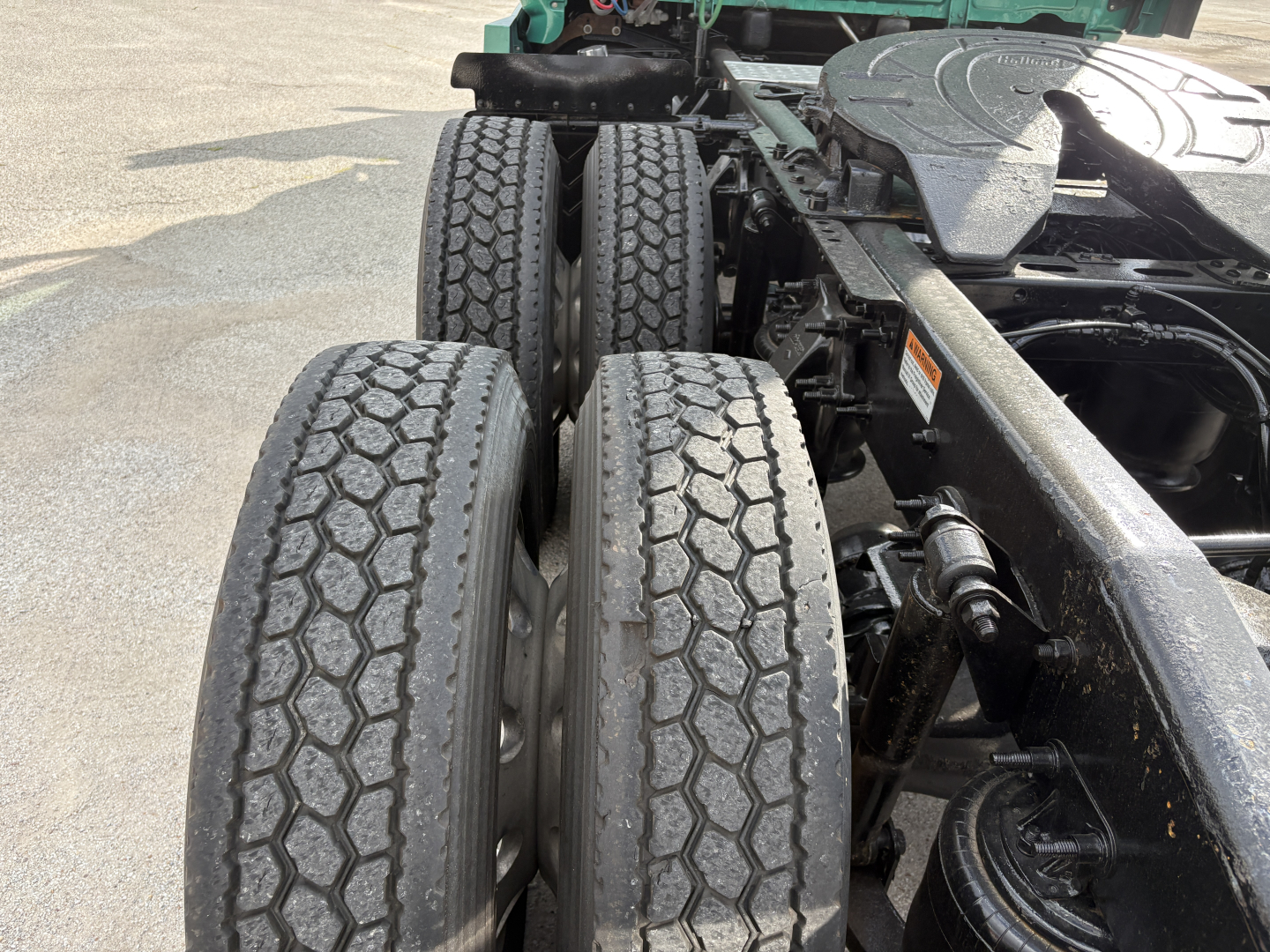 Two rear truck axles with dual tires and a metal frame, showing the wheel ends and suspension components.