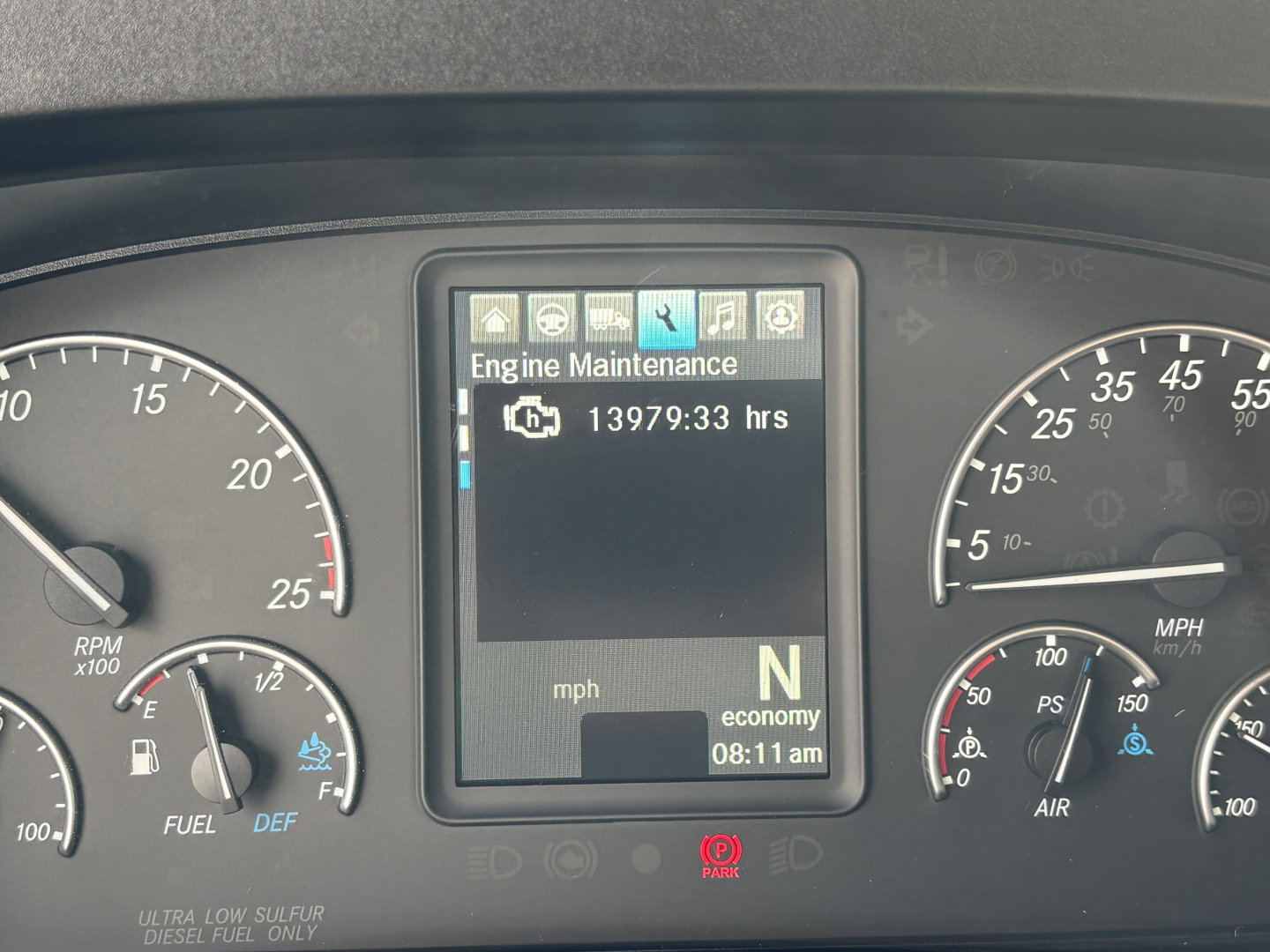Dashboard of a Freightliner Cascadia 126 showing engine maintenance screen with hour meter 13979.93 hrs, gear N, and analog gauges including RPM, speed, and fuel.
