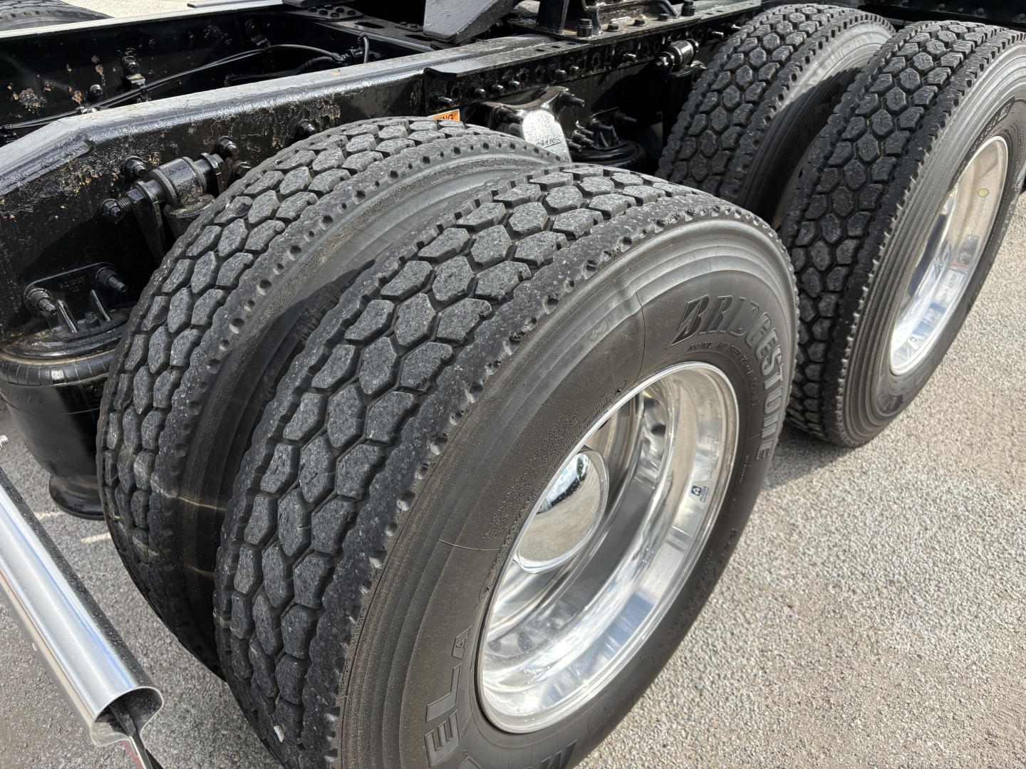 Truck axle area with dual rear tires and chrome rims on a Freightliner Cascadia 126, showing treaded tires and wheel hubs.