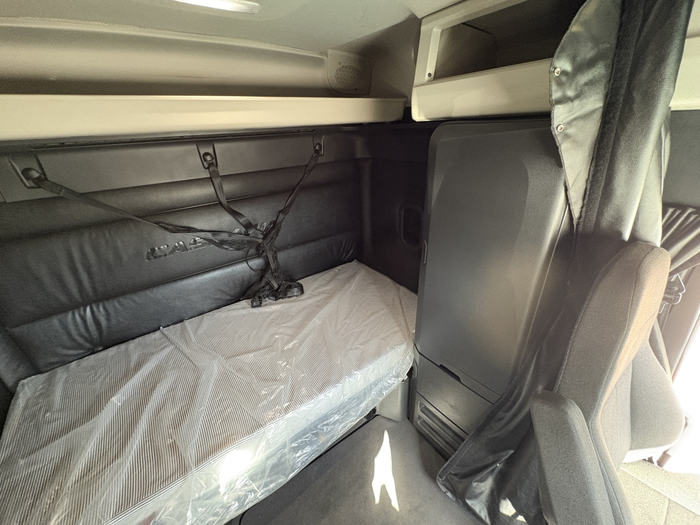 Freightliner Cascadia 126 sleeper cab interior with bunk bed and window shade visible.