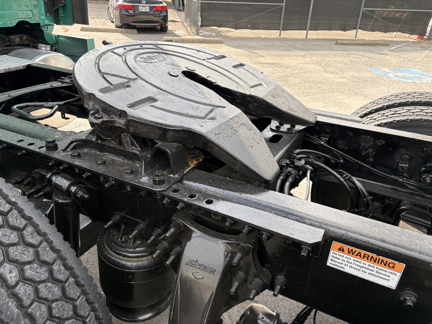 Freightliner Cascadia 126 truck chassis showing fifth wheel and mechanical components with warning label