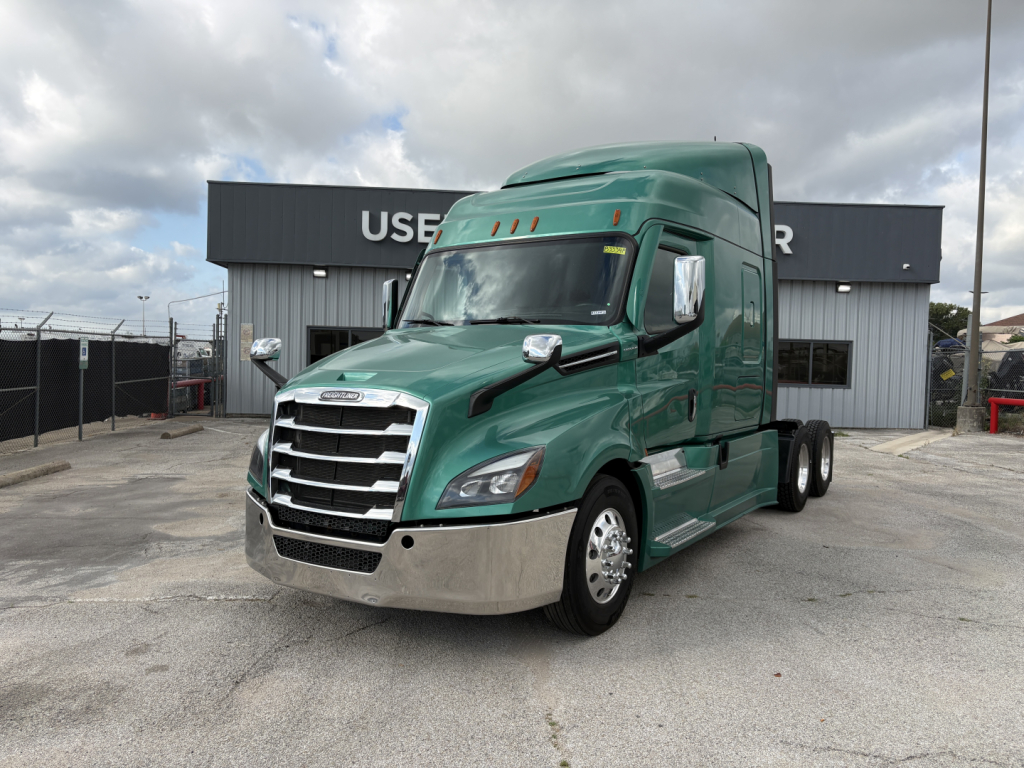 Freightliner Cascadia 126 tractor in green, front-left view, with chrome grille and bumper, sleeper cab, brand badges visible, in a dealership lot.