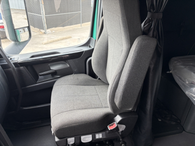 Truck cab interior showing the driver seat and passenger seat with grey fabric and armrests; window and door panel visible.