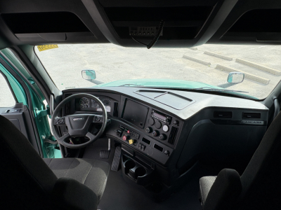 Freightliner Cascadia 126 truck cabin interior view from the driver seat showing steering wheel, dashboard, and center console.