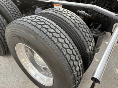 Dual rear truck tires on a Freightliner Cascadia 126 tractor showing tread pattern and chrome wheel, part of the chassis and exhaust nearby.