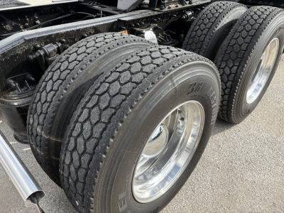 Truck axle area with dual rear tires and chrome rims on a Freightliner Cascadia 126, showing treaded tires and wheel hubs.