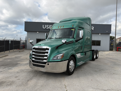 Freightliner Cascadia 126 tractor in green, front-left view, with chrome grille and bumper, sleeper cab, brand badges visible, in a dealership lot.