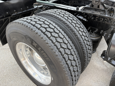 Dual rear truck tires with tread pattern visible, wheel rim, and suspension components of a Freightliner Cascadia 126 chassis.