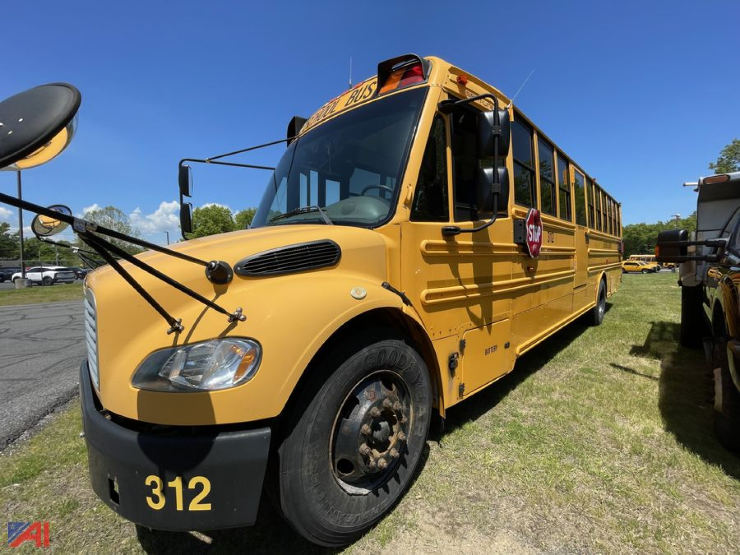 School bus showing front left side of a yellow 2013 Freightliner C2, bus number 312, with stop sign and school bus lights, in a parking lot.
