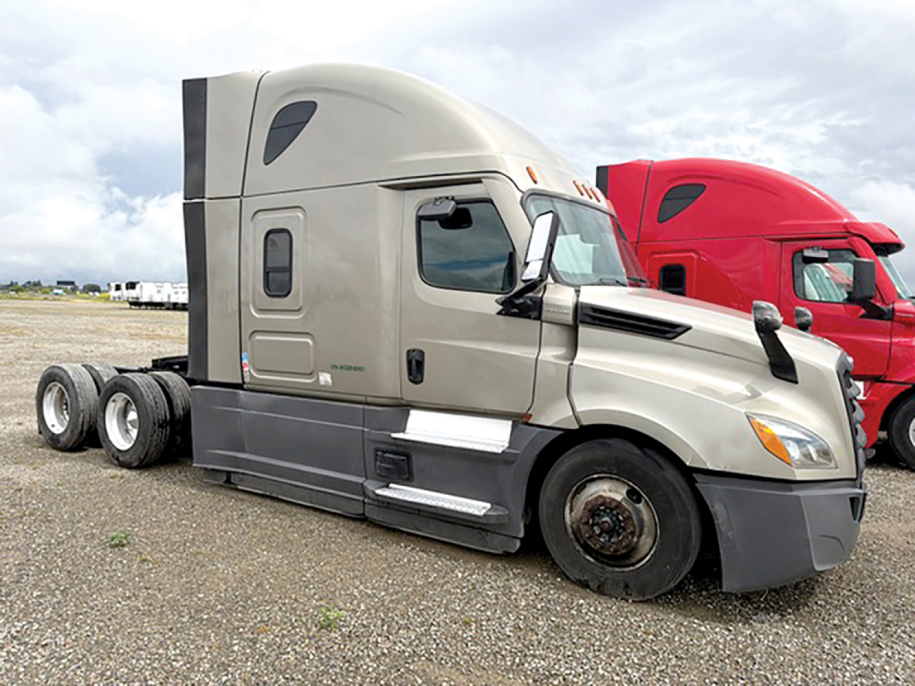 Freightliner Cascadia126 conventional sleeper truck in a gravel lot, front and side view, with beige cab and black lower trim.