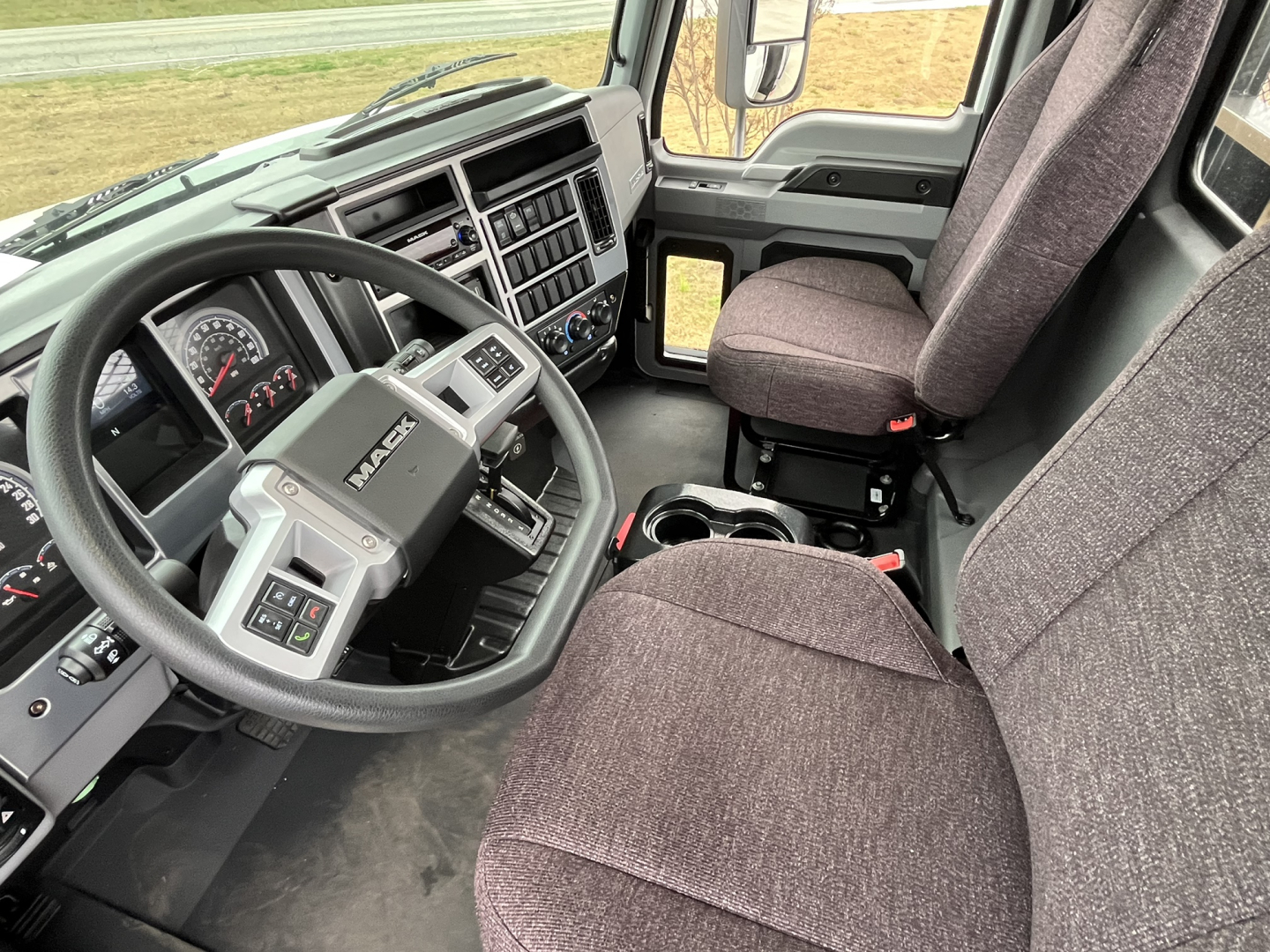 Interior view of a 2026 Mack MD6 truck cab showing steering wheel, dashboard, and front seats.