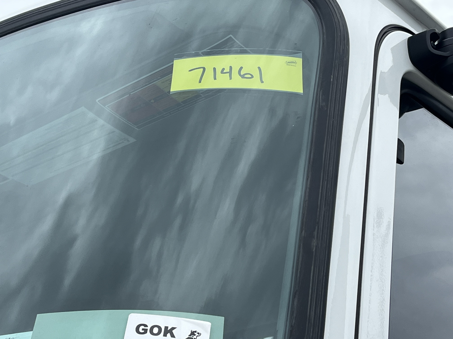 Truck window with yellow stock tag reading 71461 and a stickered windshield tag visible on the Mack MD6 listing.