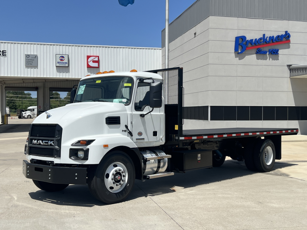 Mack MD6 flatbed truck in white showing front grille and cab, with flatbed cargo area and side railing.