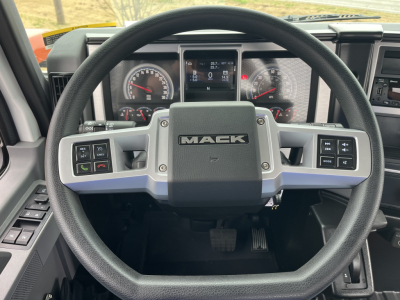 Mack MD6 steering wheel and dashboard view showing gauges and digital display with Mack logo on horn center.