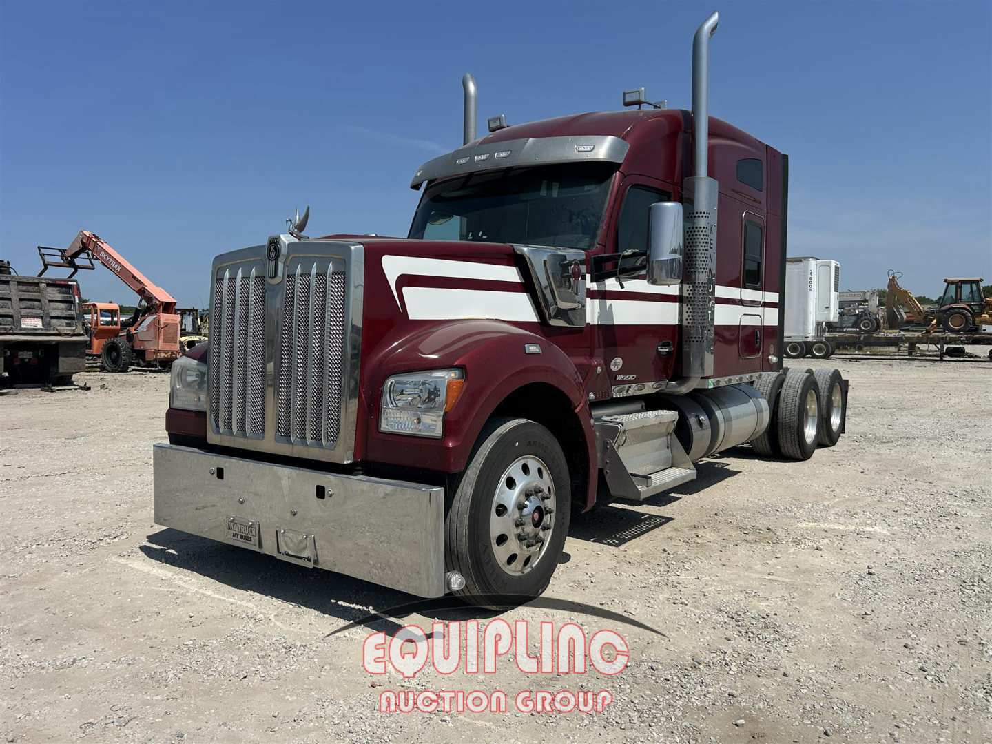 Kenworth W900 truck with maroon color and chrome grille, showing dual exhaust stacks, long hood, and tandem rear axles in a yard.