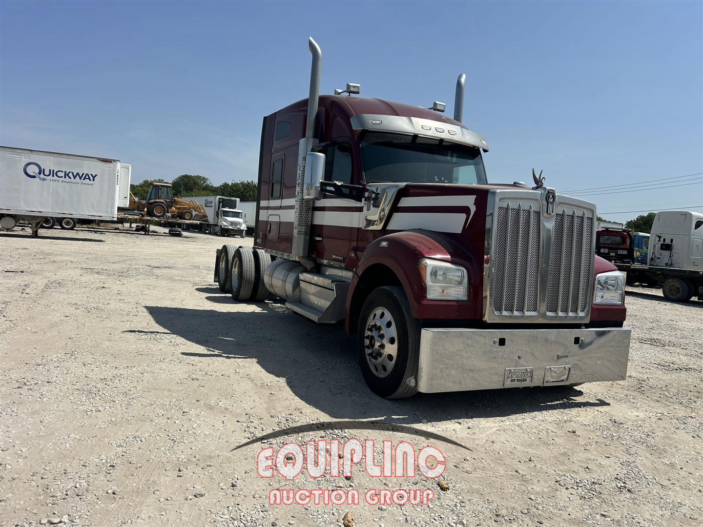 Kenworth W900 conventional sleeper truck in maroon with chrome grille and steel bumper, side exhaust stacks, parked on gravel lot.