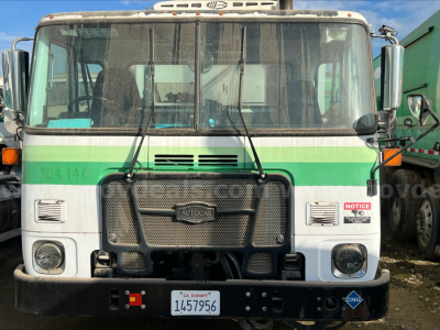 Autocar ACX XPeditor truck front view with green stripe, large grille, and bumper; visible windshield wipers and side mirrors.