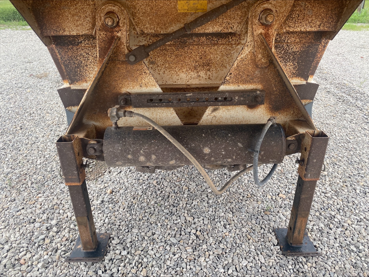 Dump trailer hitch area showing rusty wheel-lift legs and hydraulic cylinder with hoses on Armor Lite SBD40 skeleton undercarriage.