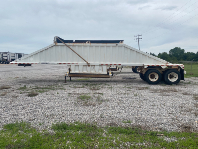 Dump trailer in side view showing Armor Lite SBD40 skeleton dumping trailer with dual rear axles and white-gray body.