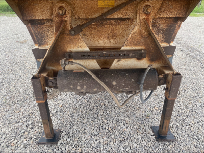 Dump trailer hitch area showing rusty wheel-lift legs and hydraulic cylinder with hoses on Armor Lite SBD40 skeleton undercarriage.