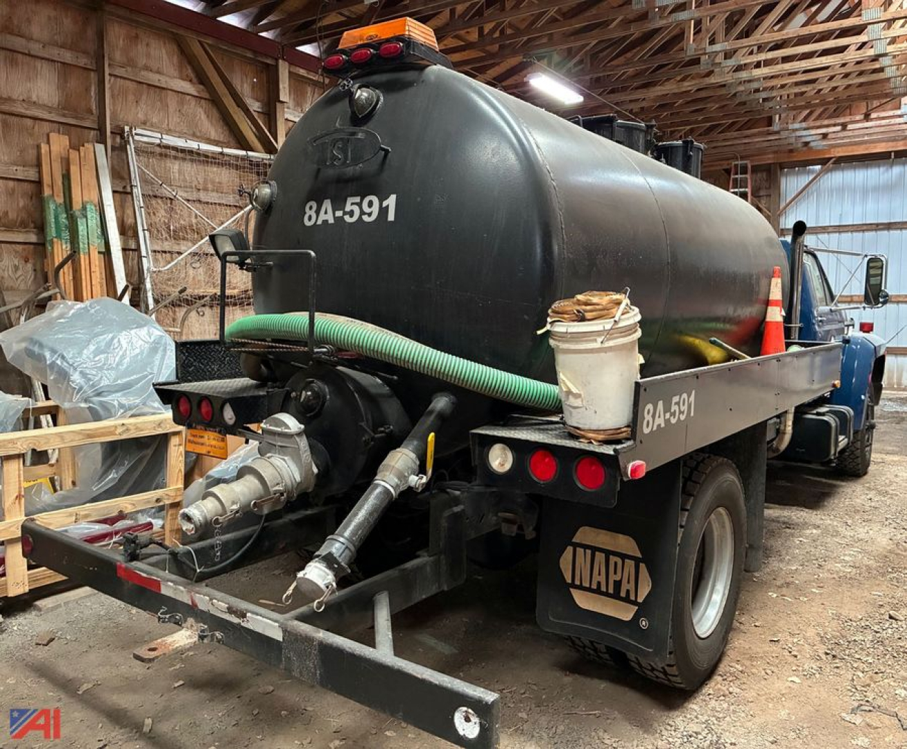 Ford F-800 septic tank vac truck rear view showing large black cylindrical tank, hose reels, and NAPA sticker.
