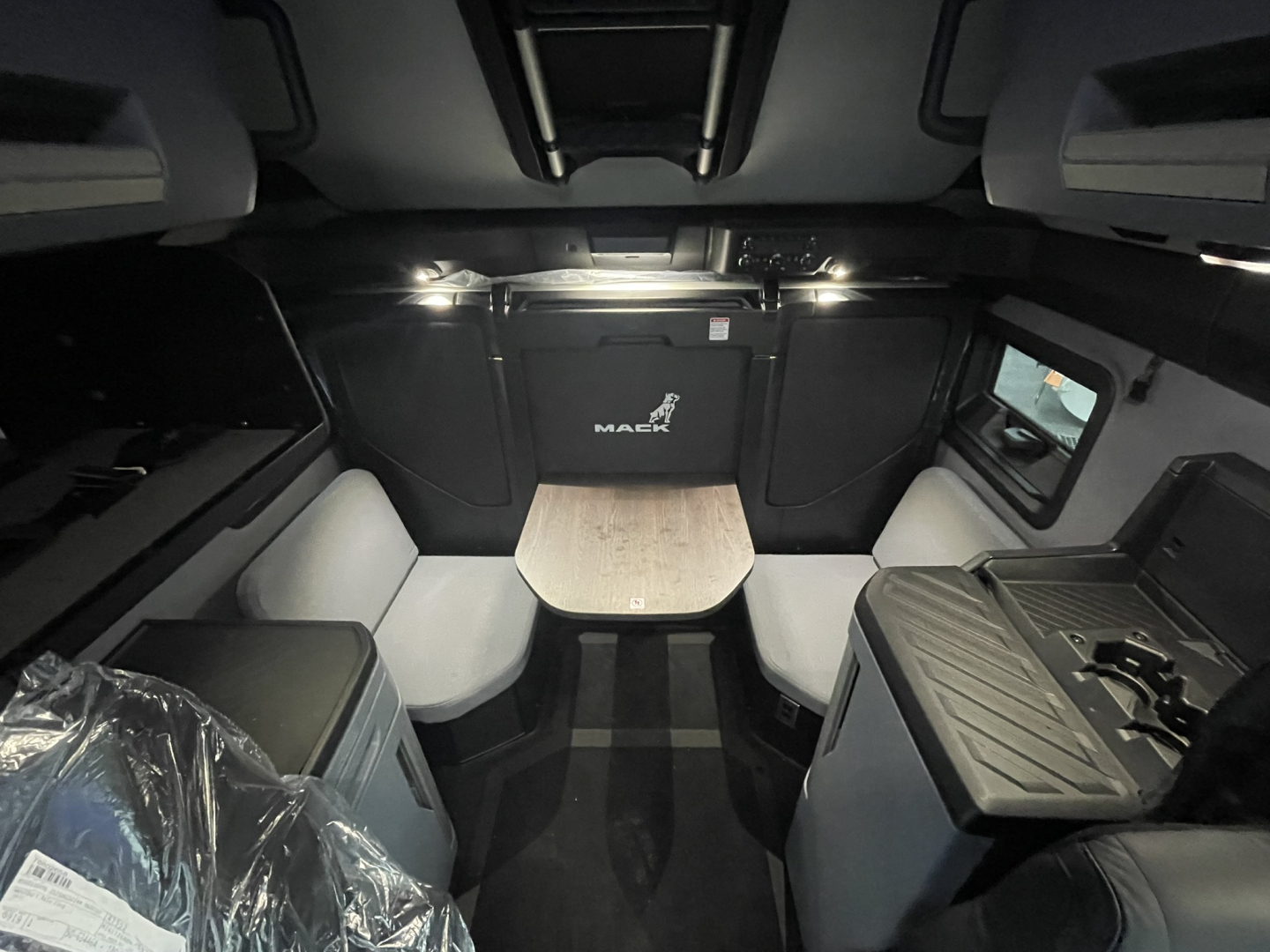 Cabin interior of new Mack PR64T76H sleeper showing dining table with two booth seats and front hatch