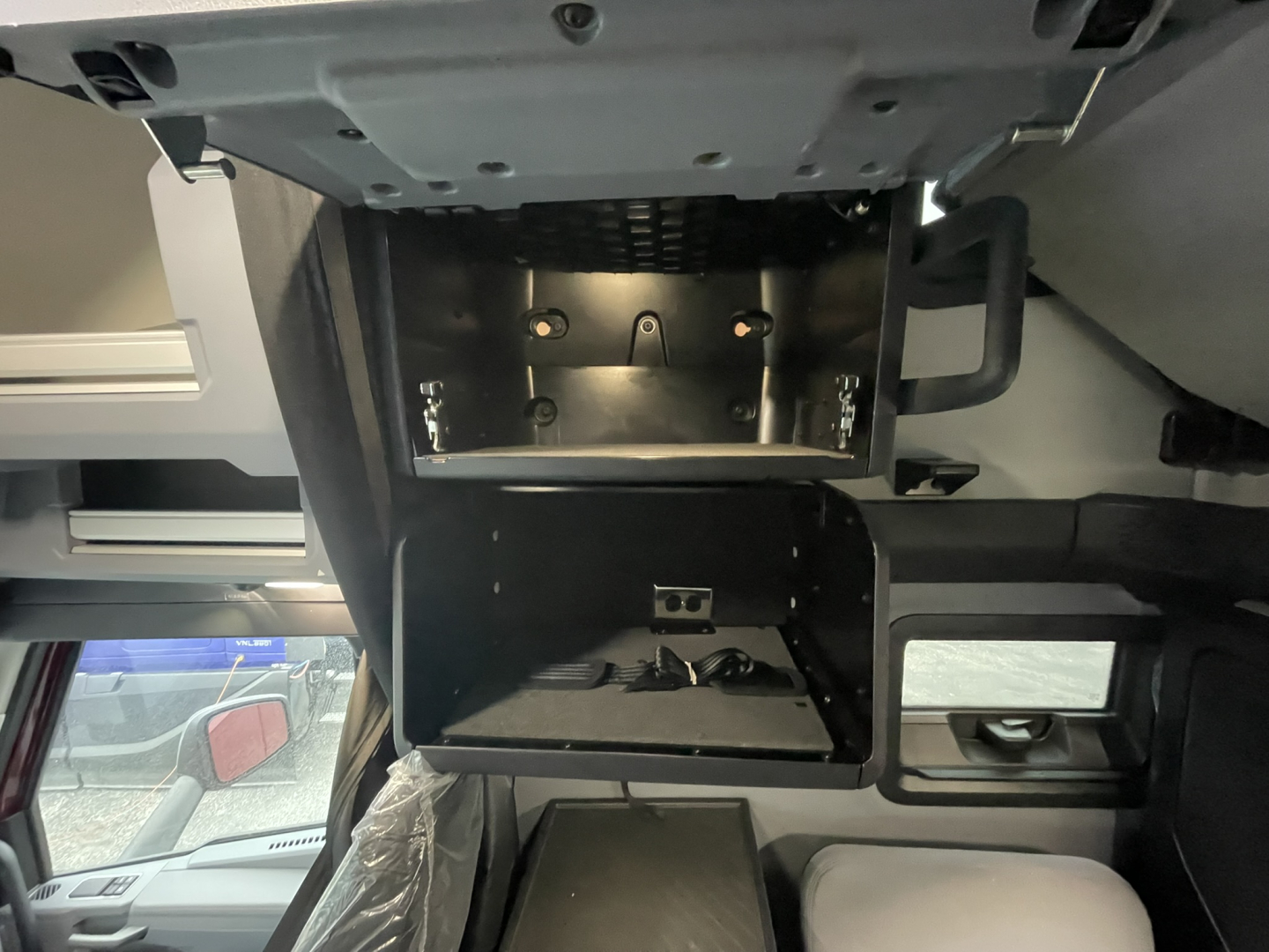 Dashboard area of a 2026 Mack PR64T76H showing an overhead storage/console with mounting brackets and open compartments.