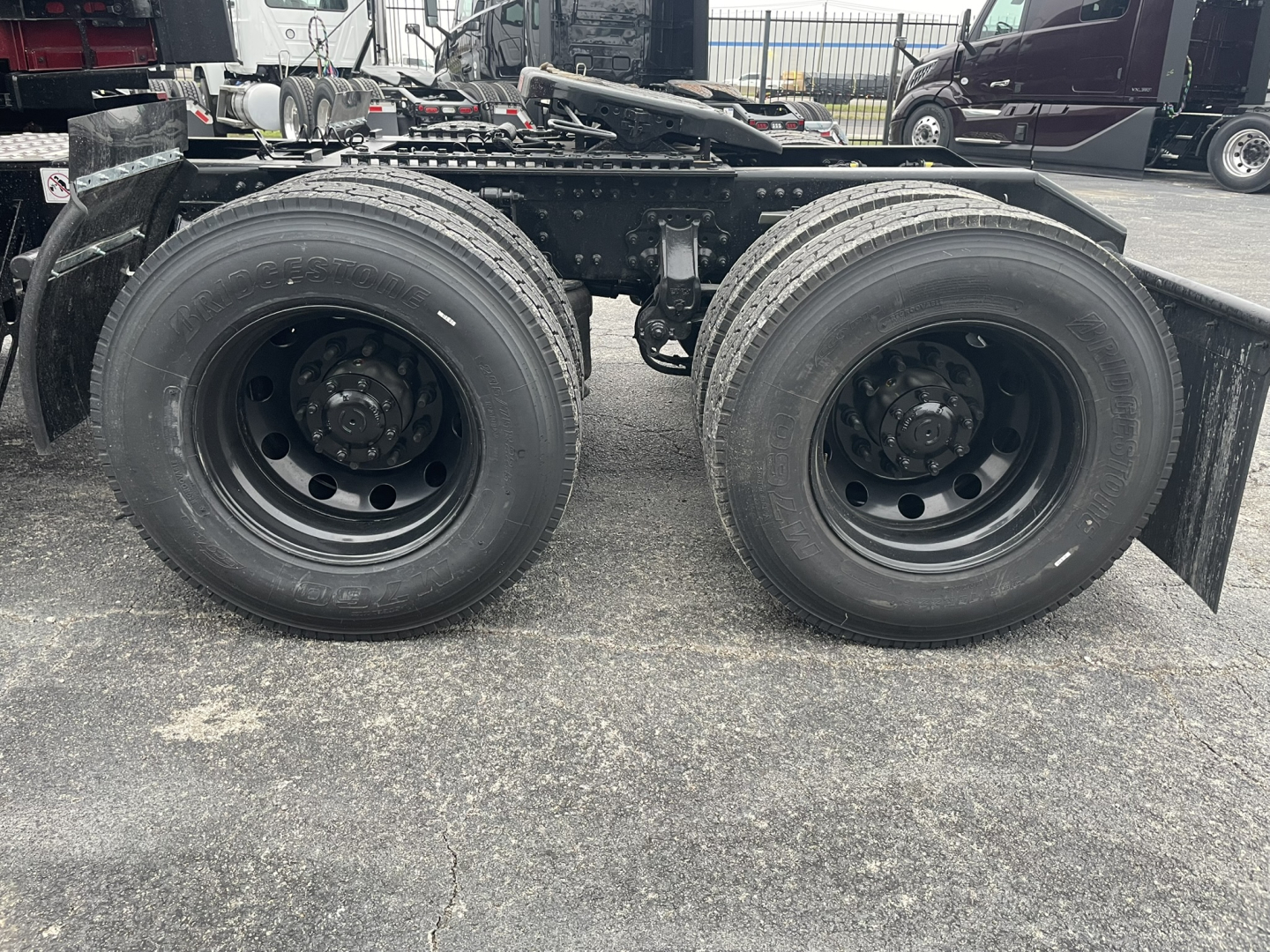 Two rear axles of a Mack PR64T76H truck showing dual-drive wheels and suspension components.