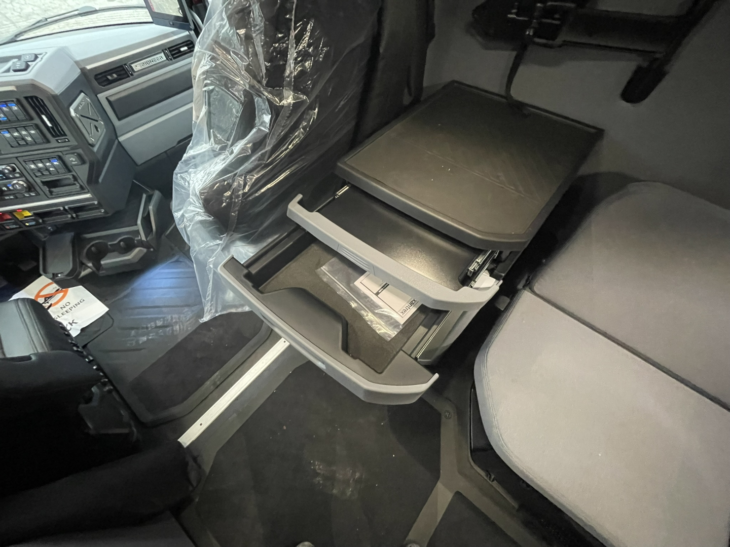 Truck interior: front cab with open center console drawer, fold-out tray, and seating; dashboard and steering wheel visible.
